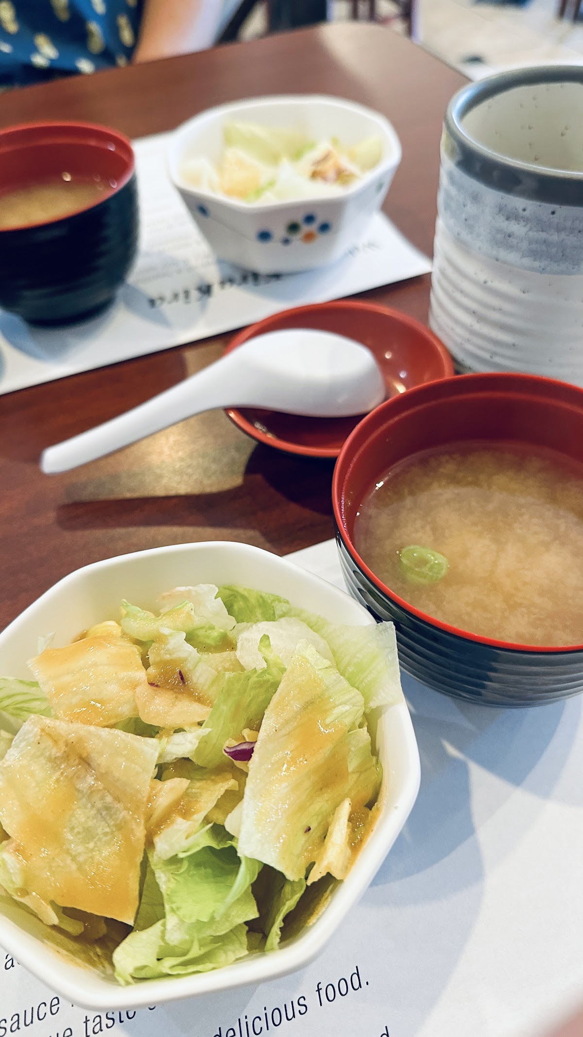 A bowl of iceberg salad under Kira Kira's own ginger dressing, next to a lacquer bowl of miso soup